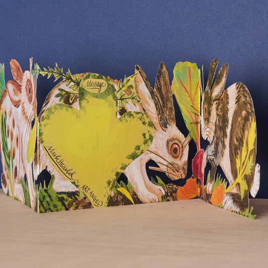 Mark Hearld Three Fold Rabbits accordion greeting card showing the hidden clover-shaped message panel surrounded by illustrated rabbits and woodland foliage.