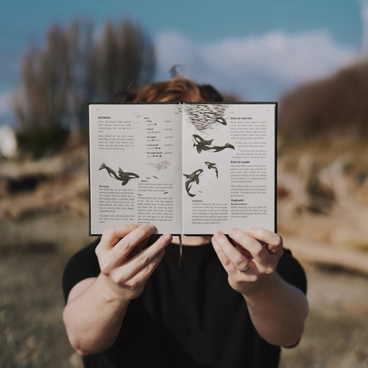 pnw card games book, pacific northwest inspired games, megan wyreweden art, thomas cardwell game designer, nature themed card games, foraging card games, orca salmon mushroom games, coastal forest games, pacific northwest game night, illustrated card game book, camping games with deck of cards, solo and group card games, pnw camping activities, original card games book, pacific northwest gifts, travel