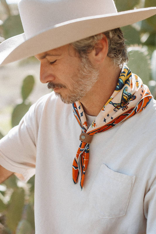 The Desert Sun Bandana by Bandits Bandanas features original artwork by Michael Matheson (Metal Teepee) and is made from Fair Trade Certified, 100% organic cotton. Soft, breathable, and versatile, this 21" × 21" bandana is perfect for hair, neck, or bag styling. Each purchase gives back, with 10% of proceeds supporting the International Rescue Committee, making it a meaningful, artist-driven accessory designed to be lived in.