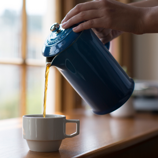 Pouring freshly brewed Sightglass Coffee from a French press into a ceramic mug by a sunny window.