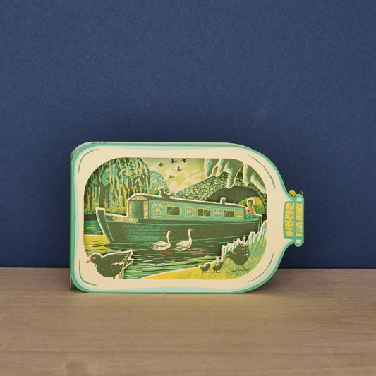 Front of Tom Jay Canal Boat in a Bottle die-cut greeting card shaped like a glass bottle featuring a colorful narrowboat, swans, and canal wildlife.