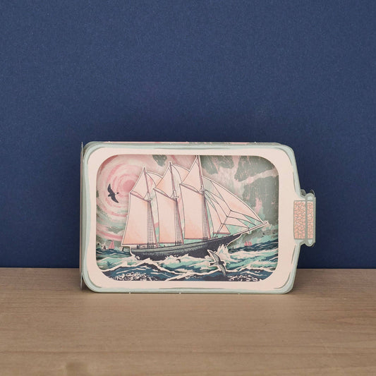 Tom Jay Schooner in a Bottle die-cut greeting card shaped like a glass bottle featuring a schooner sailing across rolling waves.