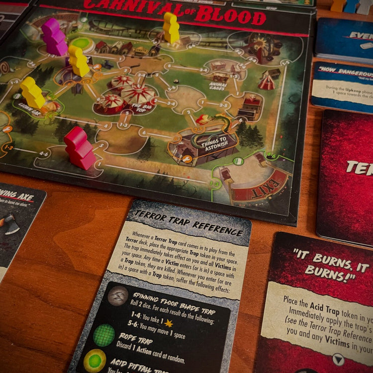 Final Girl: Carnival of Blood gameplay setup displayed on a play mat, featuring cards, tokens, character boards, and carnival-themed horror game components arranged for play.