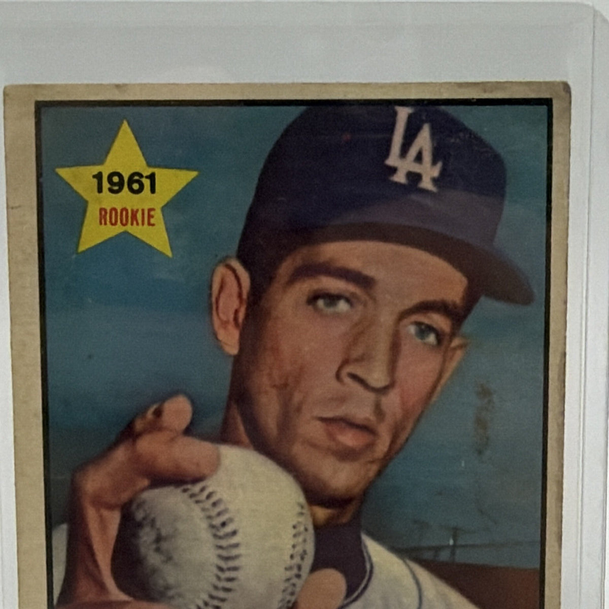 Close-up of Jim Golden holding a baseball while wearing a Dodgers cap
