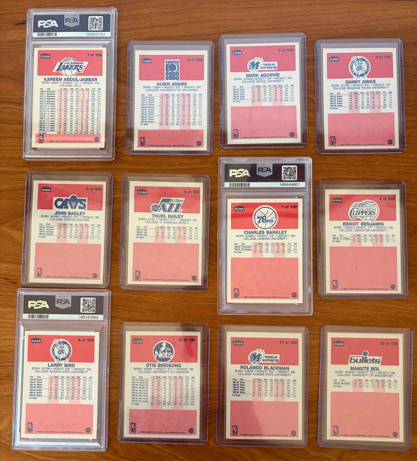 Backs of 1986 Fleer Basketball cards #1–12 displayed from the complete 1986–87 Fleer Basketball set. Featured graded cards include Kareem Abdul-Jabbar #1 PSA 6, Charles Barkley rookie card #7 PSA 8, and Larry Bird #9 PSA 8. Also shown are Alvan Adams #2, Mark Aguirre #3, Danny Ainge #4, John Bagley #5, Thurl Bailey #6, Benoit Benjamin #8, Otis Birdsong #10, Rolando Blackman #11, and Manute Bol #12. The card backs display player statistics, biographical information, and team logos from the iconic 1986 Fleer 
