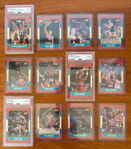 1986 Fleer Basketball cards #1–12 displayed from the complete 1986–87 Fleer Basketball set. Featured graded cards include Kareem Abdul-Jabbar #1 PSA 6, Charles Barkley rookie card #7 PSA 8, and Larry Bird #9 PSA 8. Also shown are Alvan Adams #2, Mark Aguirre #3, Danny Ainge #4, John Bagley #5, Thurl Bailey #6, Benoit Benjamin #8, Otis Birdsong #10, Rolando Blackman #11, and Manute Bol #12. Part of the iconic 1986 Fleer Basketball release.