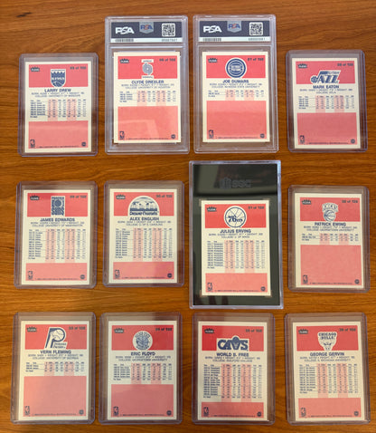 Backs of 1986 Fleer Basketball cards #25–36 displayed from the complete 1986–87 Fleer Basketball set. Featured graded cards include Clyde Drexler rookie card #26 PSA 7, Joe Dumars rookie card #27 PSA 8, and Julius Erving #31 SGC 7.5. Also shown are Larry Drew #25, Mark Eaton #28, James Edwards #29, Alex English #30, Patrick Ewing rookie card #32, Vern Fleming #33, Eric Floyd #34, World B. Free #35, and George Gervin #36. The card backs display player statistics, biographical information, and team logos from
