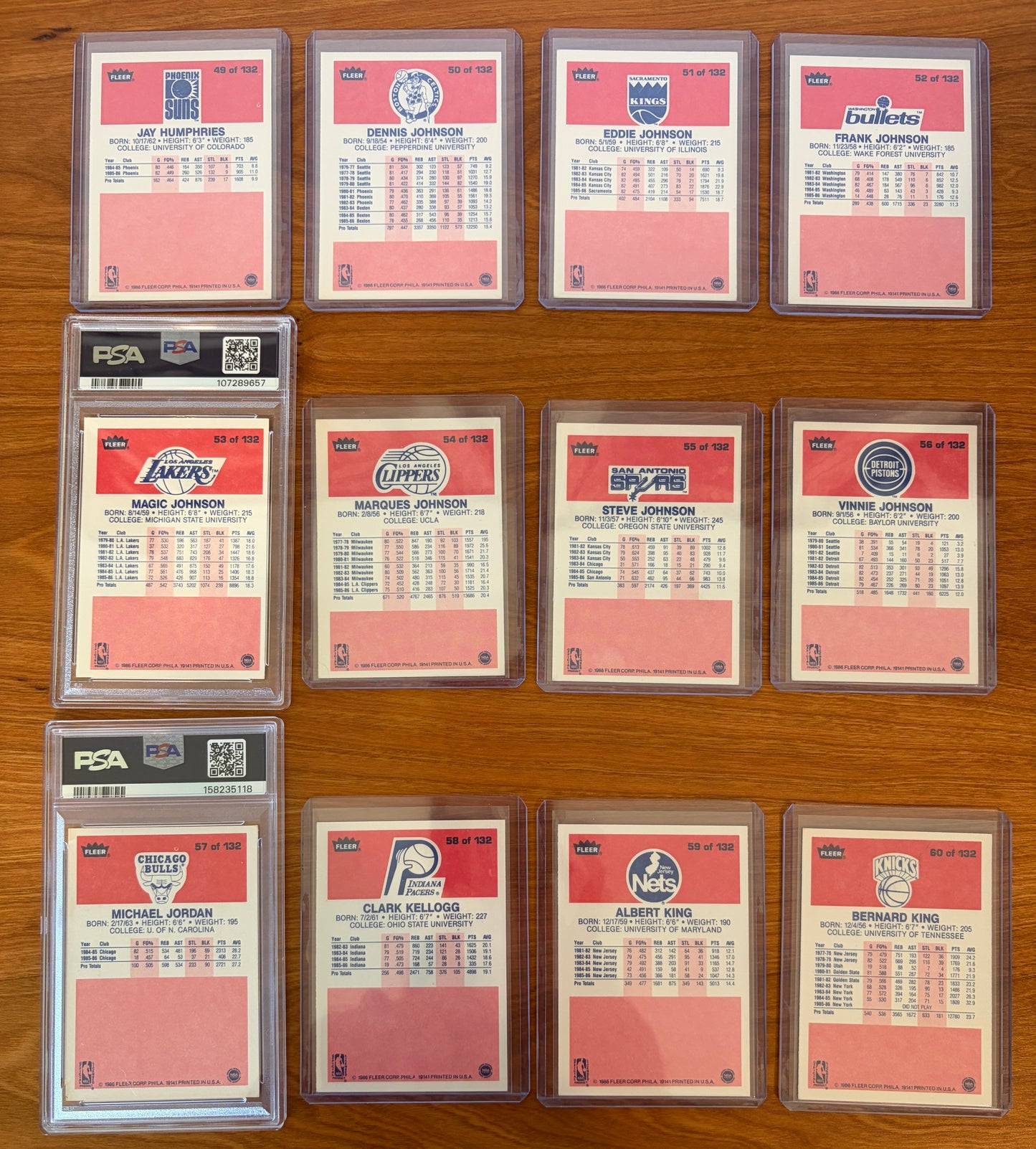 Backs of 1986 Fleer Basketball cards #49–60 featuring Magic Johnson #53 PSA 7 and Michael Jordan rookie card #57 PSA 5.5, displayed alongside neighboring cards from the complete 1986–87 Fleer Basketball set. The card backs include player statistics, biographical information, and team logos from one of the most iconic basketball card releases ever produced.