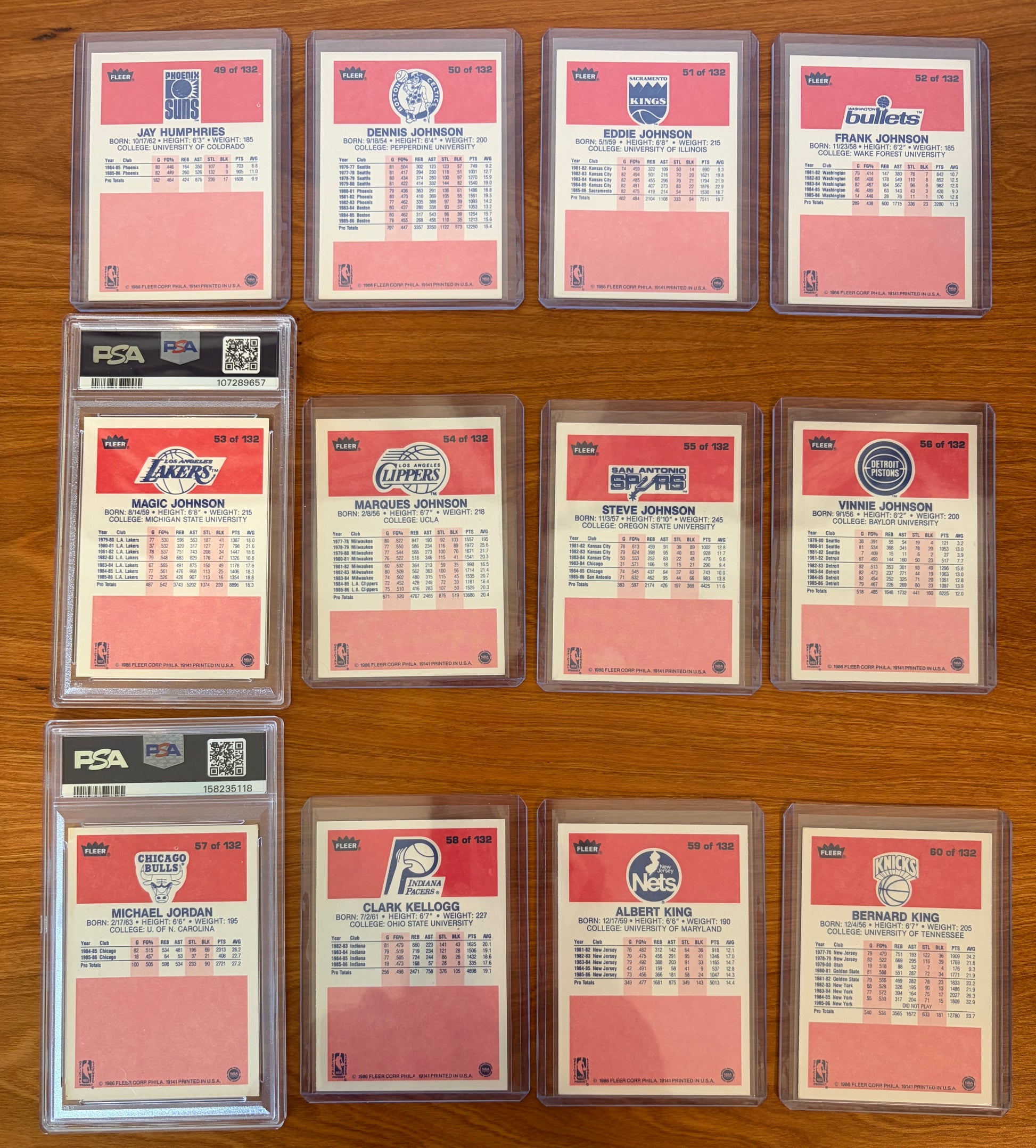 Backs of 1986 Fleer Basketball cards #49–60 featuring Magic Johnson #53 PSA 7 and Michael Jordan rookie card #57 PSA 5.5, displayed alongside neighboring cards from the complete 1986–87 Fleer Basketball set. The card backs include player statistics, biographical information, and team logos from one of the most iconic basketball card releases ever produced.
