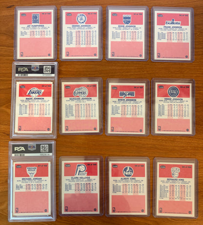 Backs of 1986 Fleer Basketball cards #49–60 featuring Magic Johnson #53 PSA 7 and Michael Jordan rookie card #57 PSA 5.5, displayed alongside neighboring cards from the complete 1986–87 Fleer Basketball set. The card backs include player statistics, biographical information, and team logos from one of the most iconic basketball card releases ever produced.