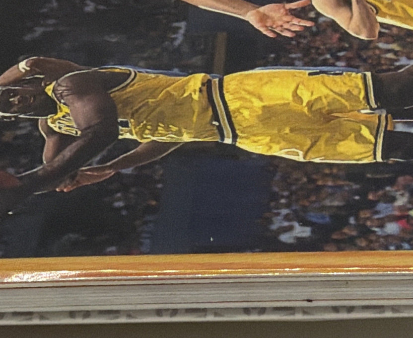 Close-up of a 1993 Classic Draft Picks basketball card showing a player in a yellow uniform, woodgrain border, and stacked card edges
