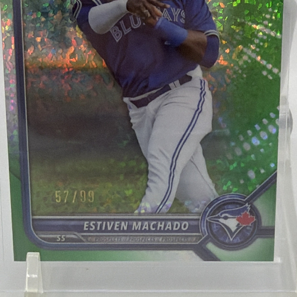 Close-up of Estiven Machado in a blue baseball uniform against the reflective green refractor background