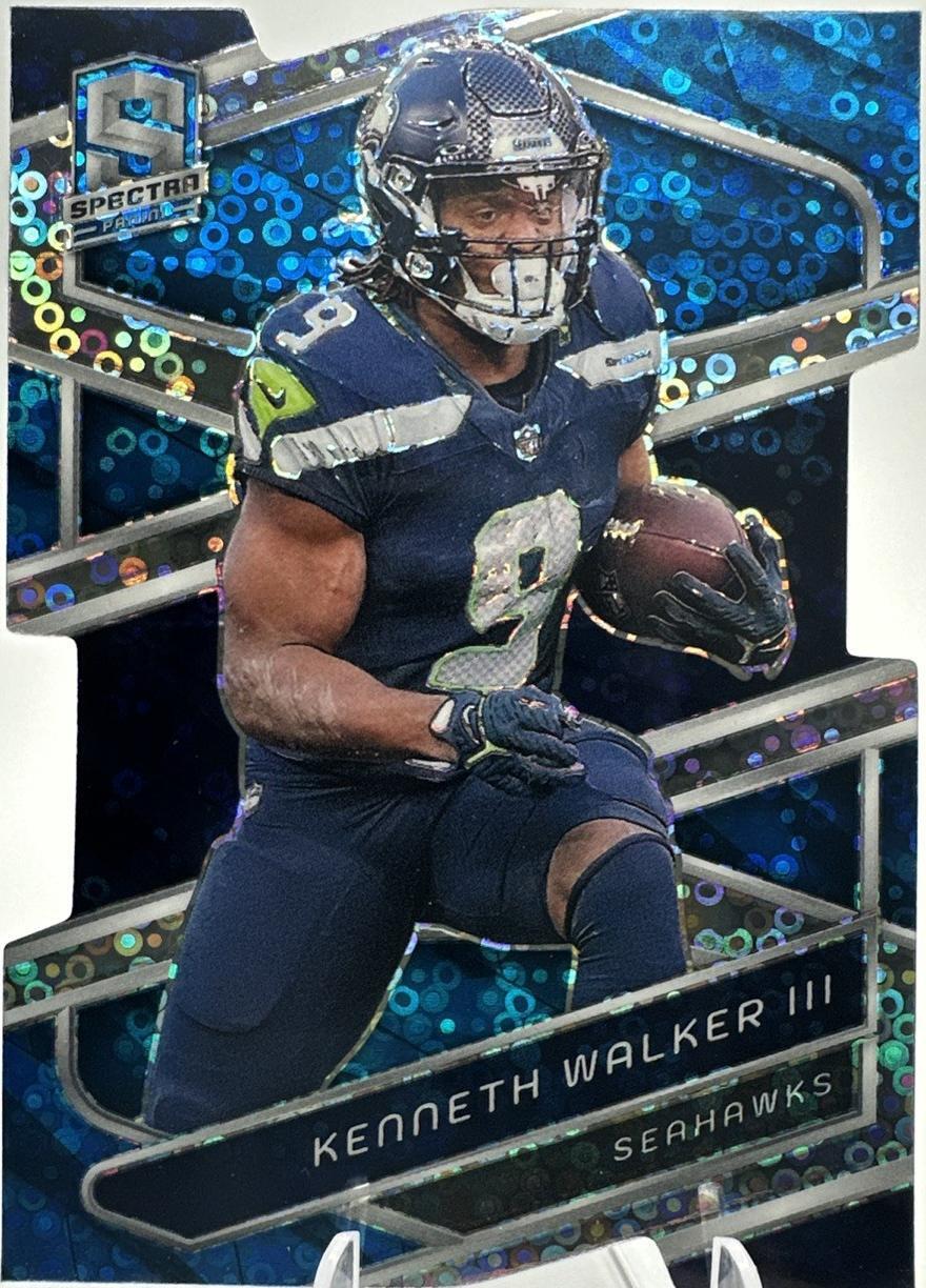 2024 Panini Spectra RC - Kenneth Walker III #92 Neon Blue Prizm Die-Cut/50 PSA 9 Close-up of 2024 Panini Spectra Kenneth Walker III Neon Blue Die-Cut parallel card, showcasing the vibrant blue prizm pattern and distinctive die-cut design.