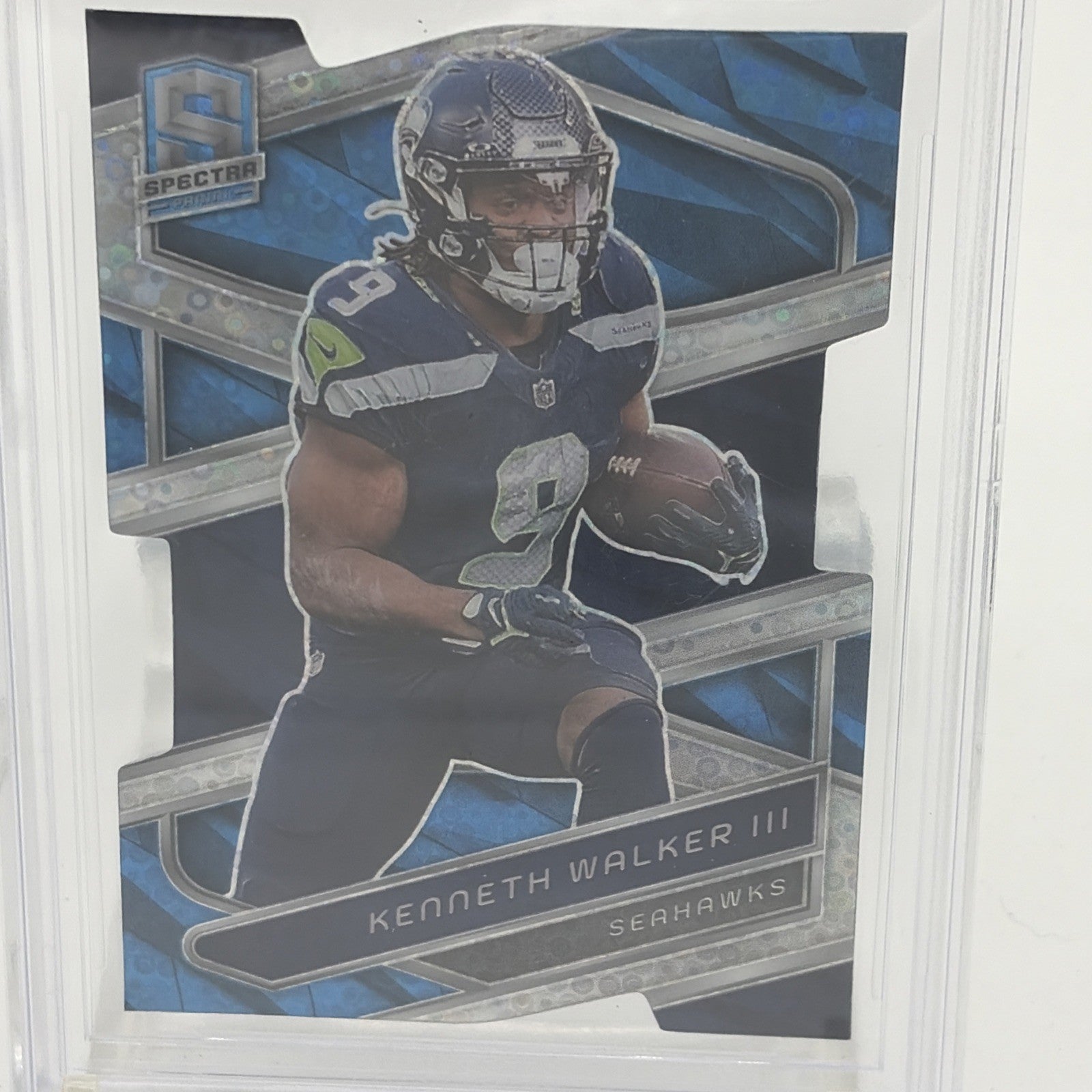 Detail view of 2024 Panini Spectra Kenneth Walker III Neon Blue Die-Cut parallel card showcasing the distinctive die-cut design and Seahawks star running back.