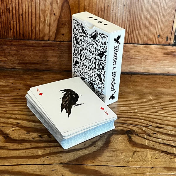 Be Like A Crow playing card deck and Murder & Mischief tuck box on a wooden table