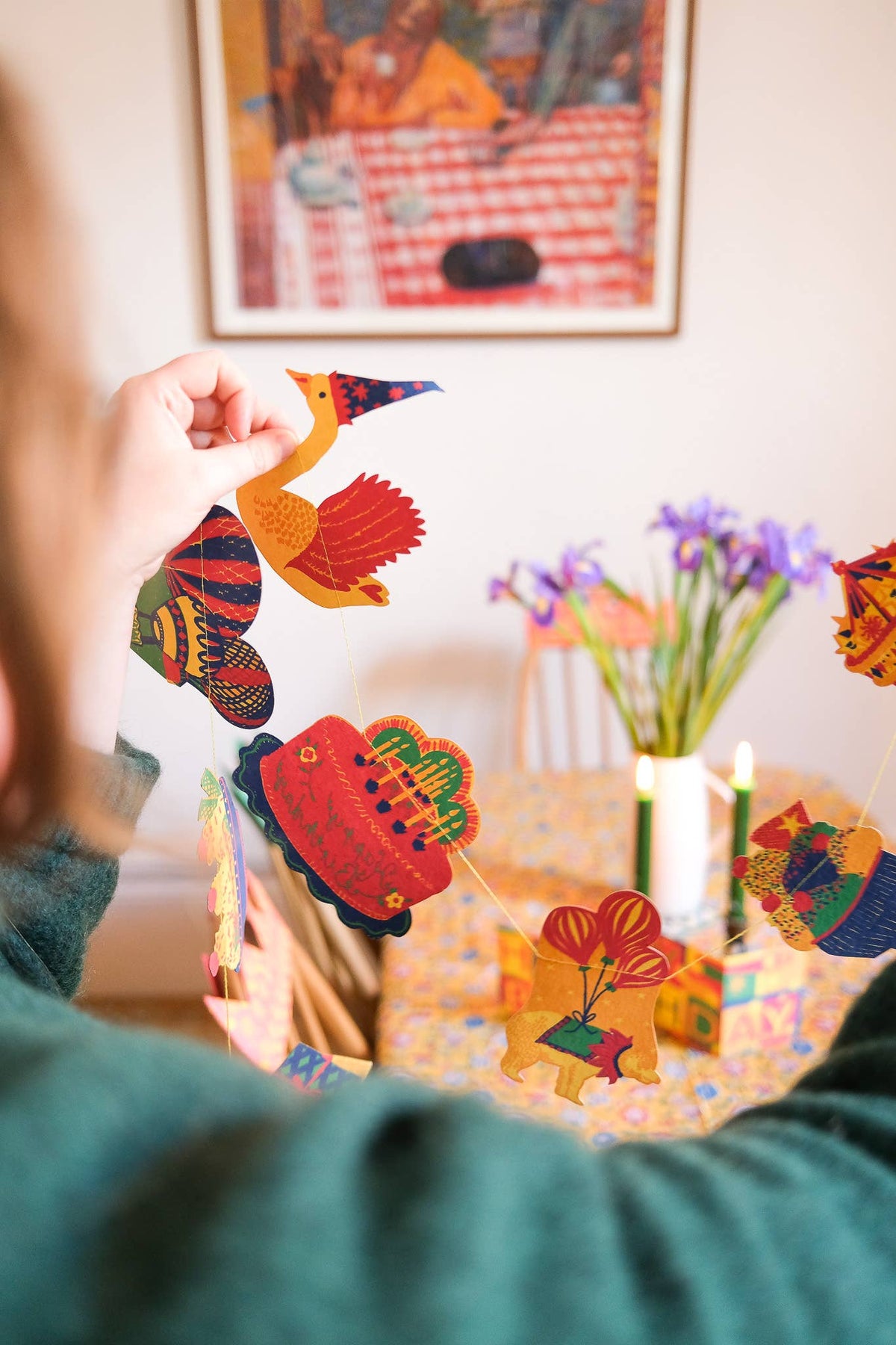 A person holding colorful East End Press sewn garland preparing to decorate a dining room for a birthday celebration