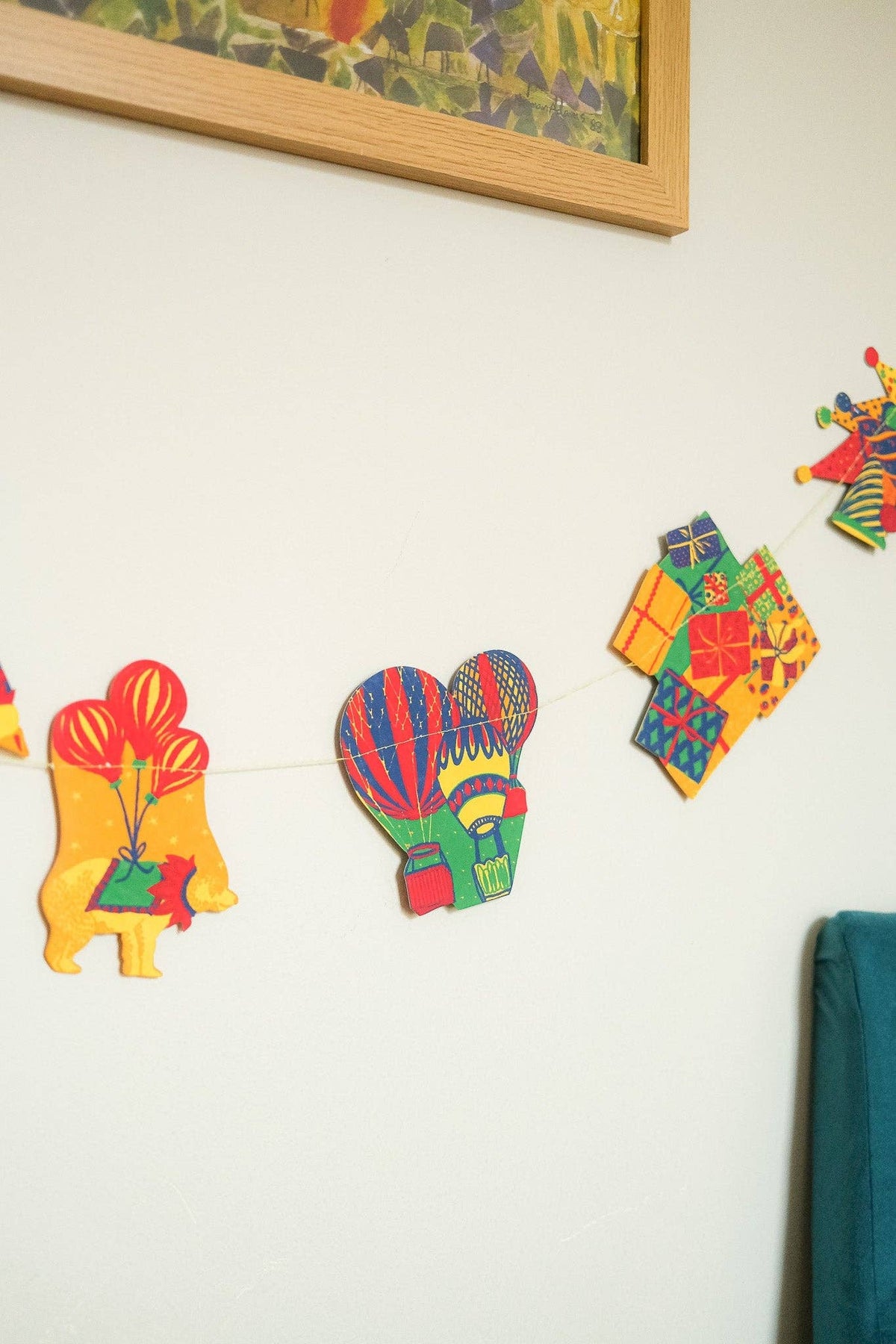 East End Press Birthday Party Garland hanging across a white wall with colorful cakes gifts and party shapes
