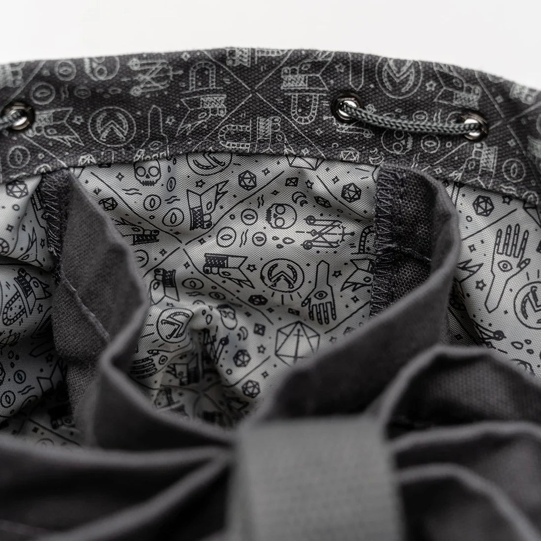 Close-up of interior patterning in Laura Bailey's dice bag of hording bag of holding.  Grey with blackline drawings of critical role icons and symbols of arcana
