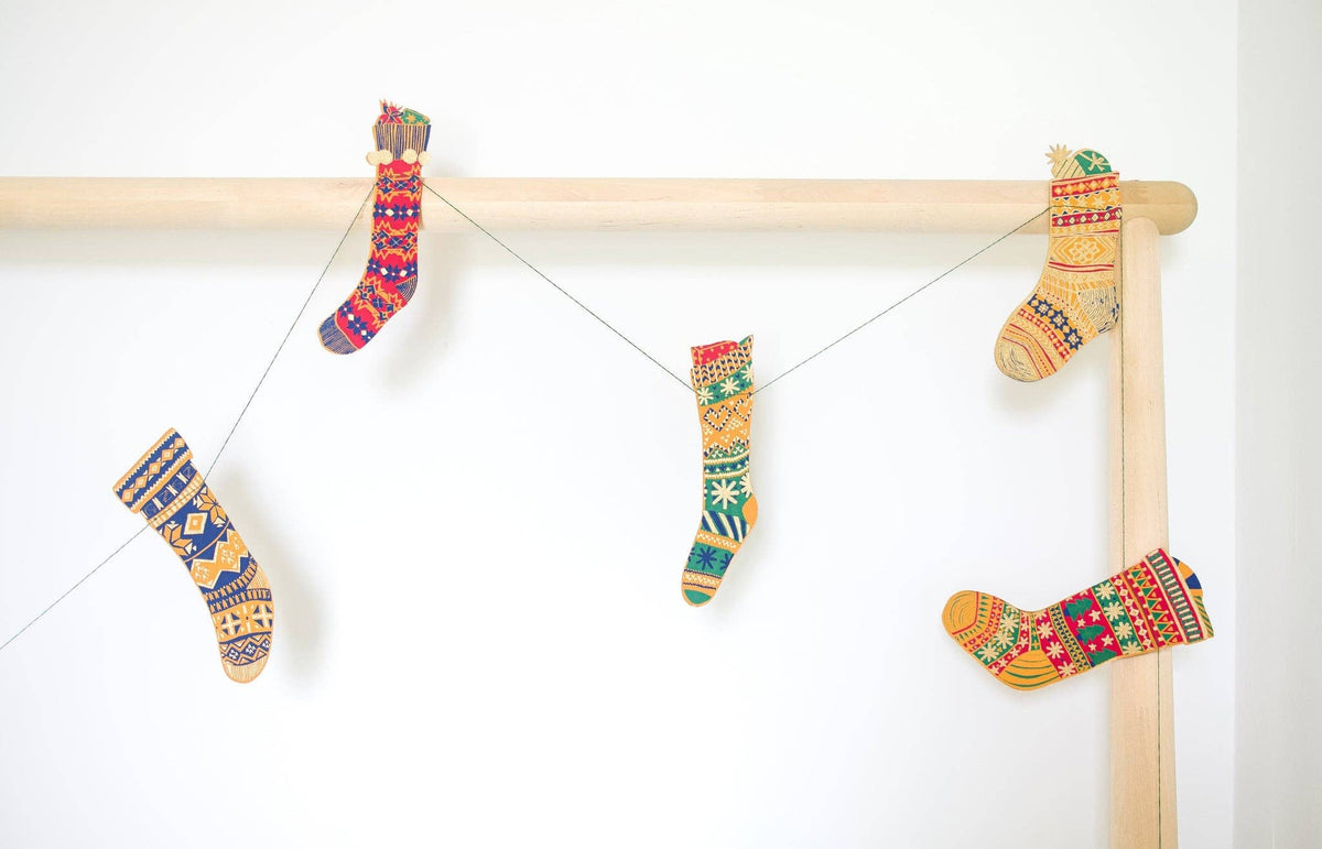 Colorful hand printed paper stockings hanging from the East End Press festive garland