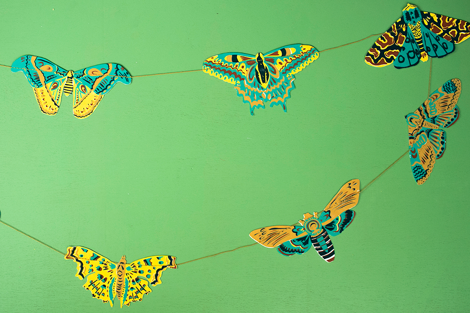 Hand printed East End Press moth garland decorating a cozy living room wall