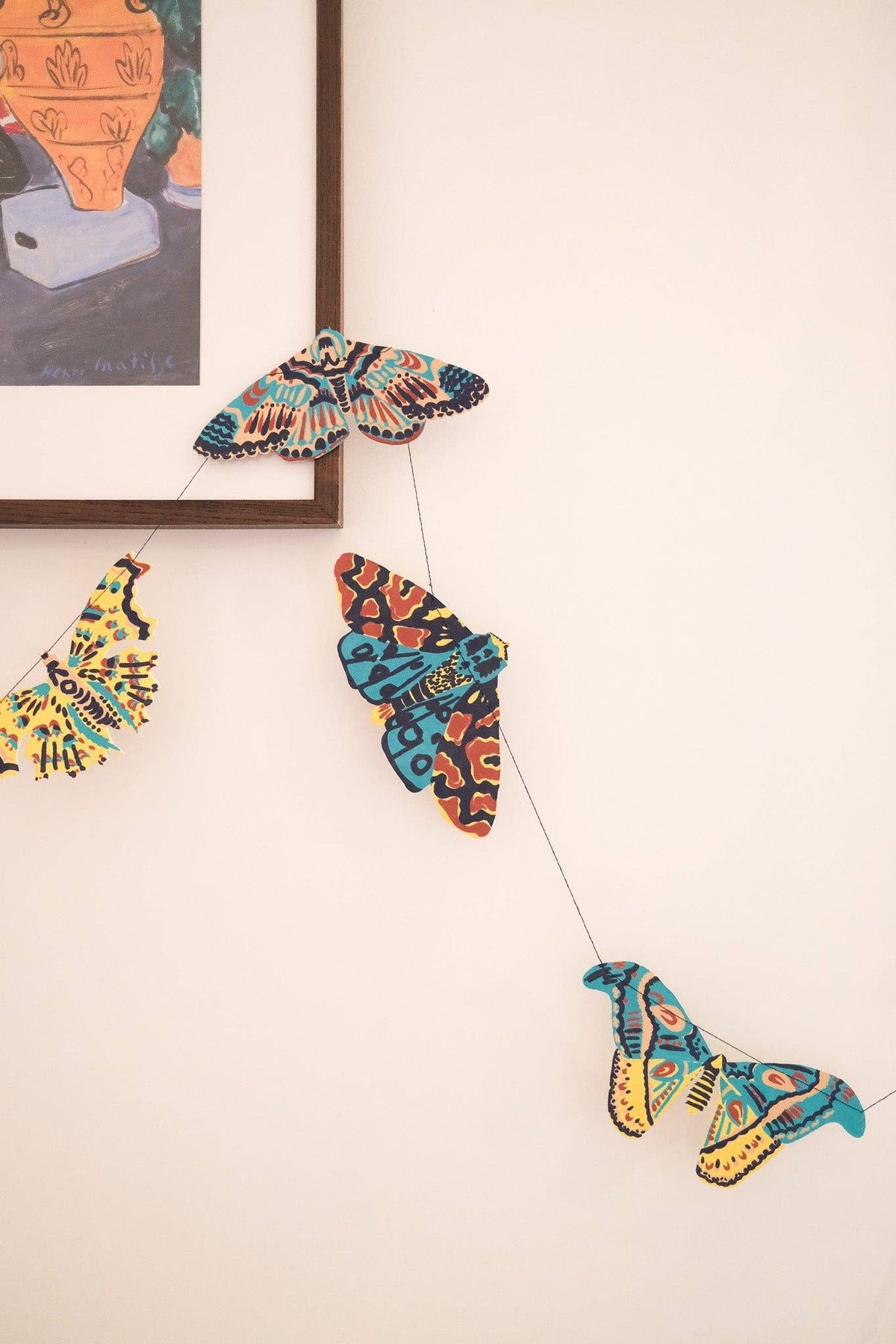 Colorful East End Press moth garland displayed across a white wall