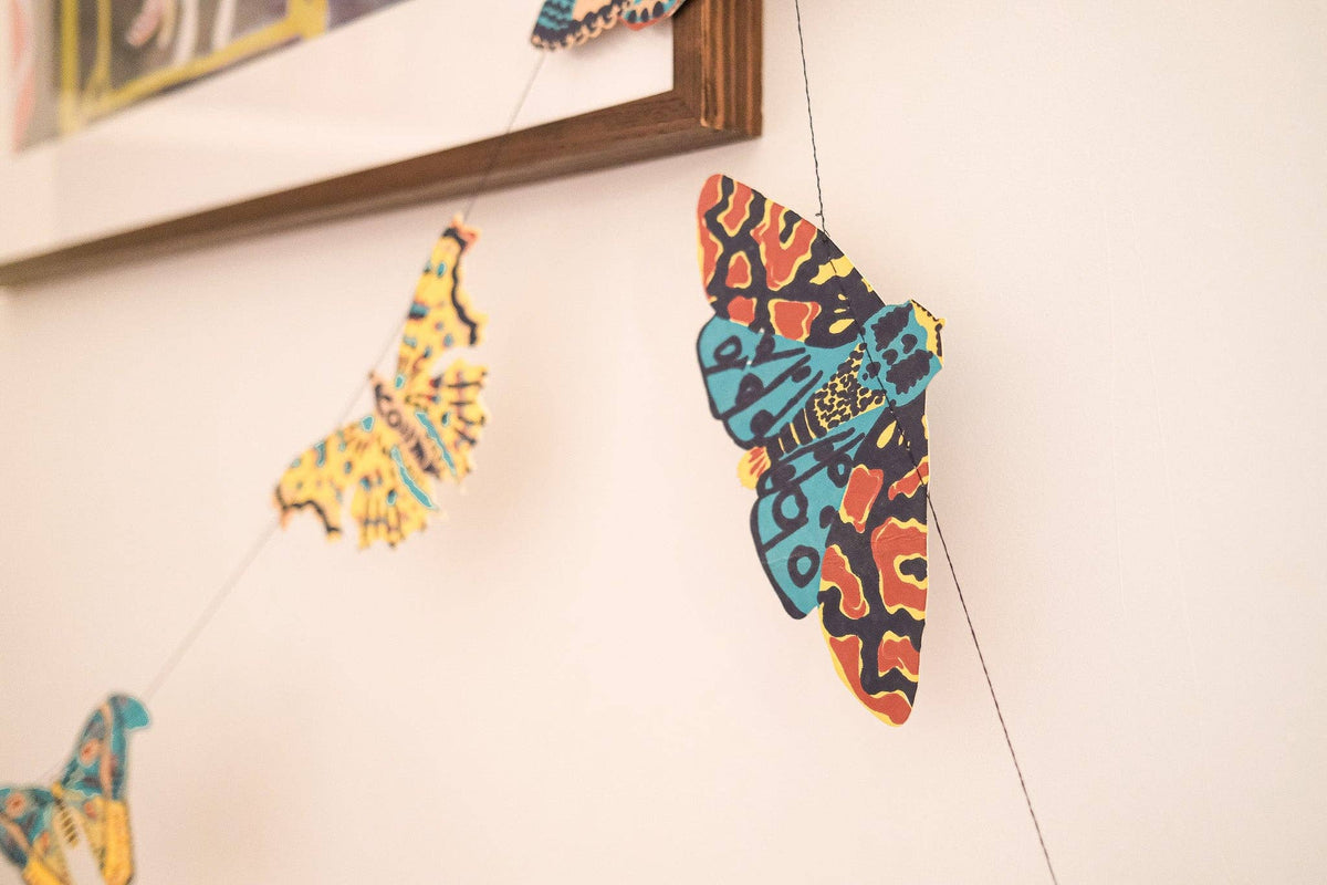 Colorful East End Press moth garland detail closeup displayed across a white wall