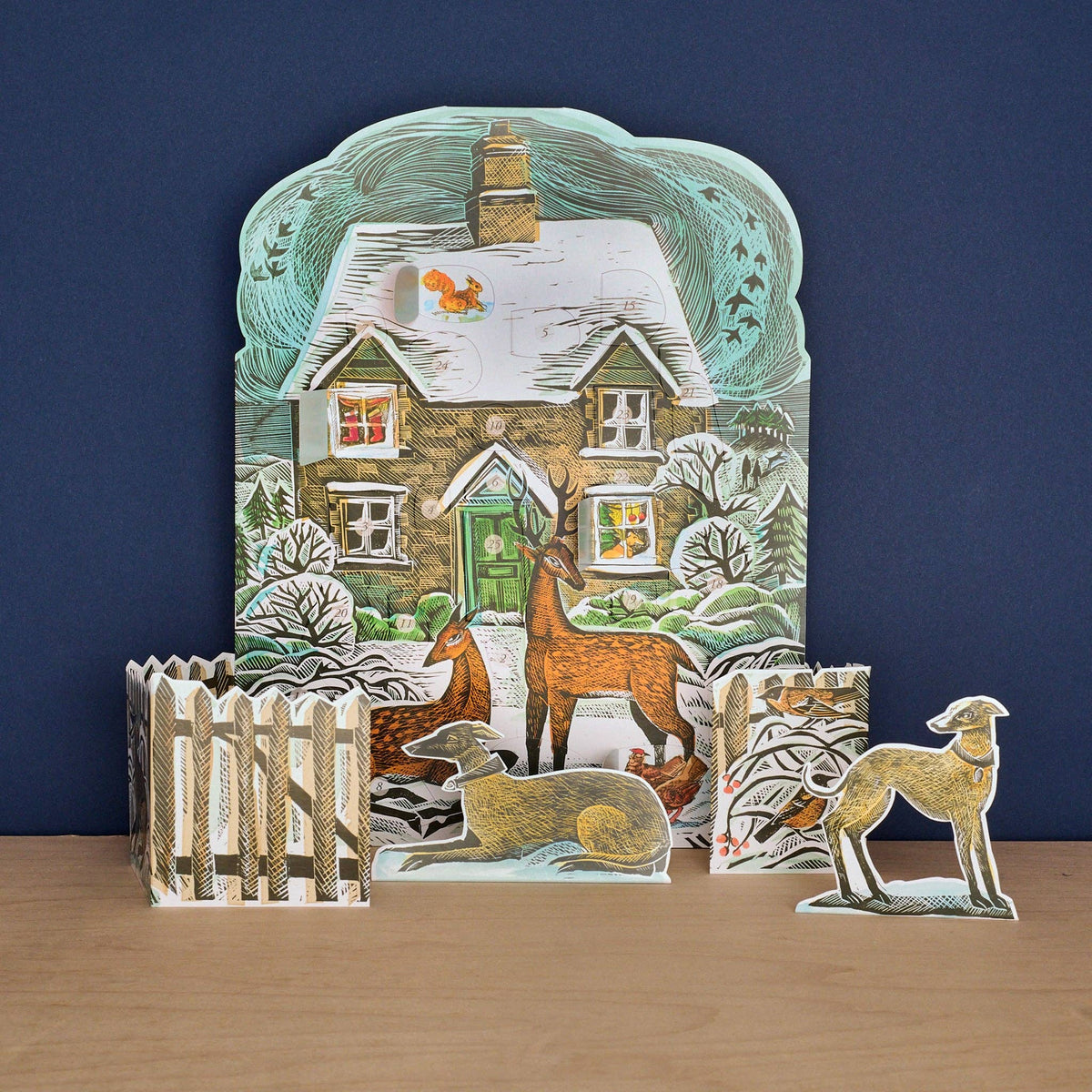 Angela Harding Christmas Cottage Advent Calendar featuring a snowy cottage with stand-up deer, birds, and 24 advent windows.