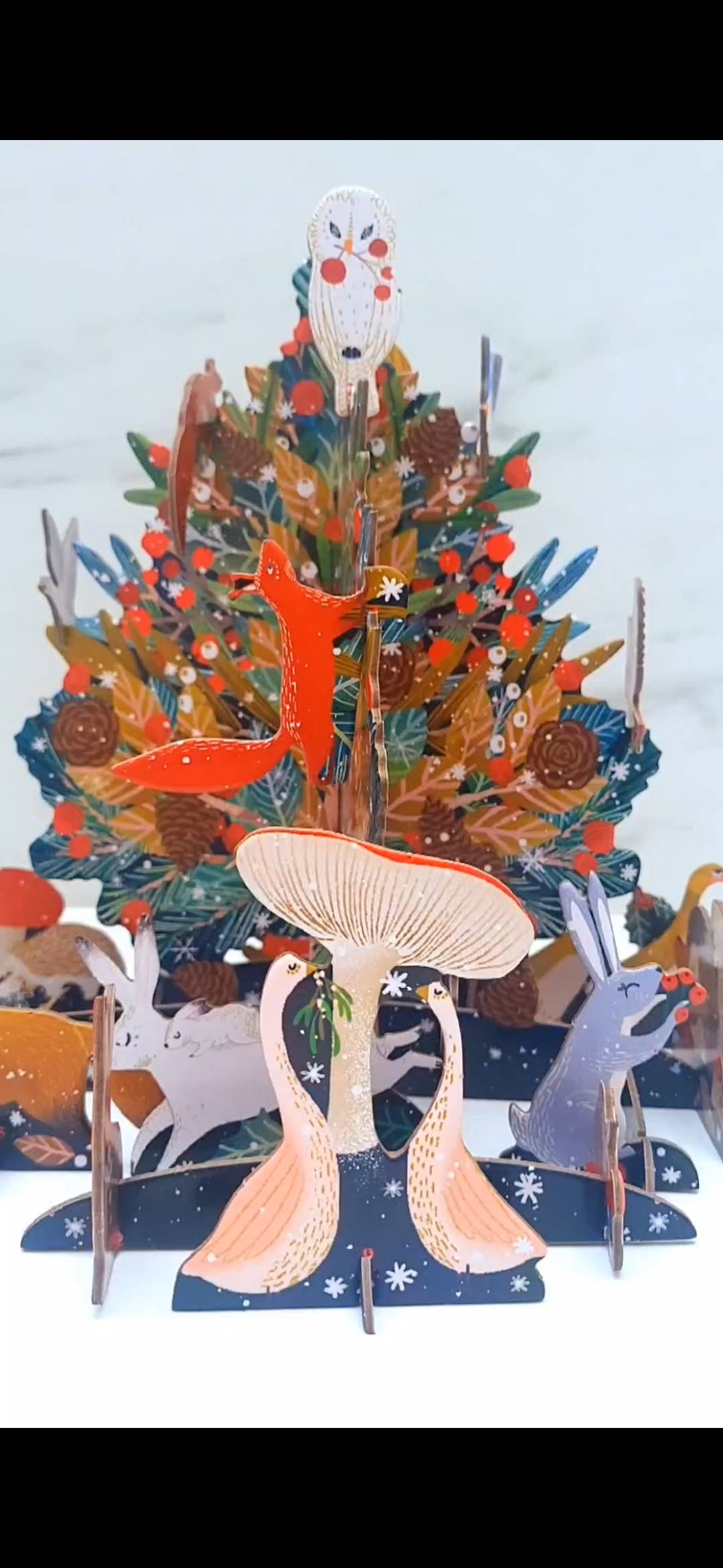 Detail of the Antoana Oreski Beneath the Tree Pop & Slot Advent Calendar featuring woodland animals, a red fox, rabbits, mushrooms, and layered Christmas tree branches.