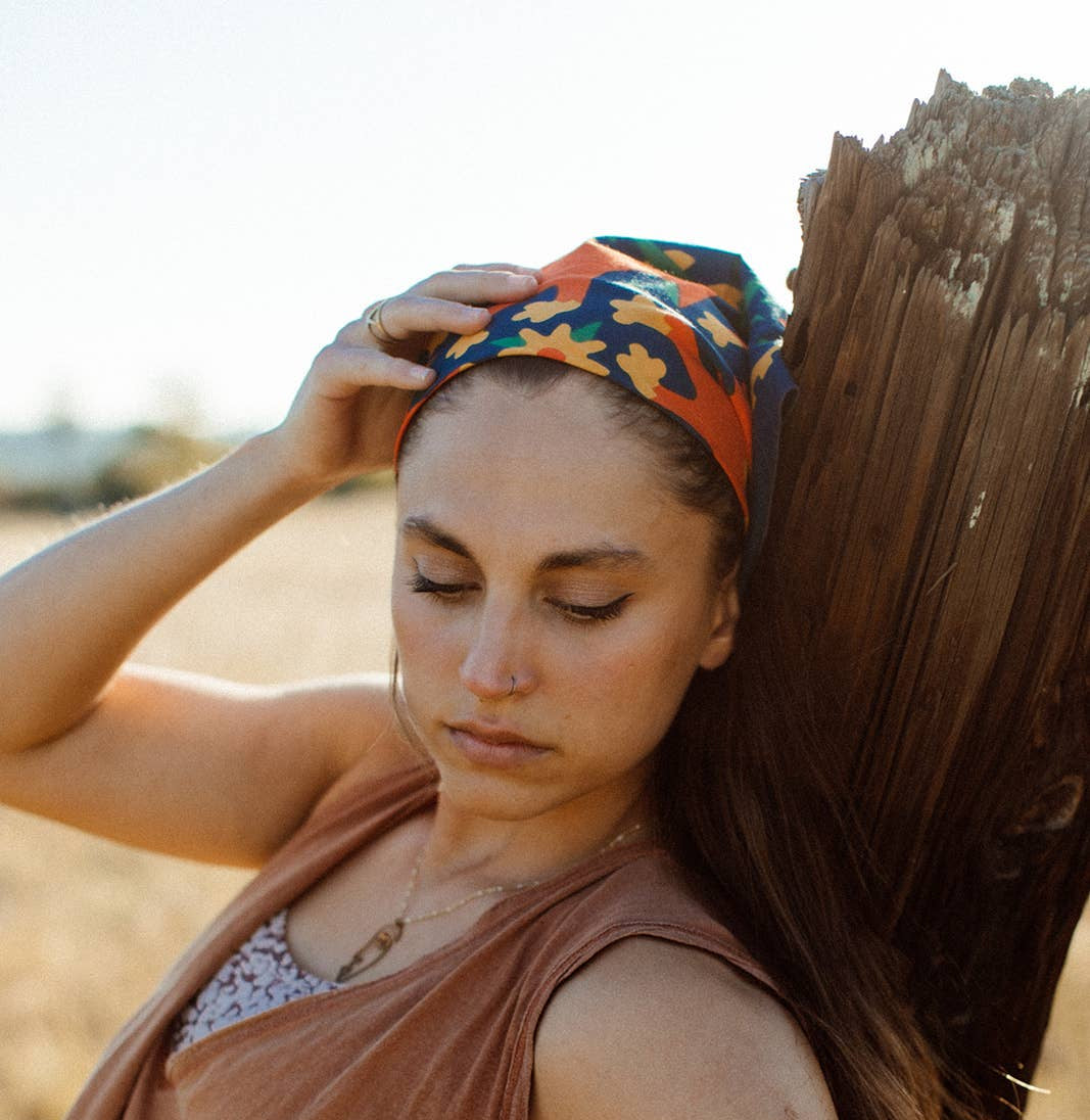 Endless Bloom bandana by Bandits Bandanas featuring four stylized orange foxes arranged in a circular floral pattern on a deep teal background with yellow flowers