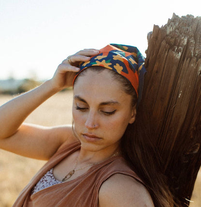 Endless Bloom bandana by Bandits Bandanas featuring four stylized orange foxes arranged in a circular floral pattern on a deep teal background with yellow flowers