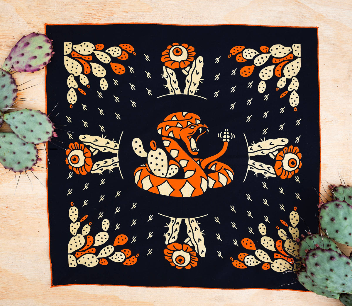 Bandits Cactus Dream bandana by Brothers Design Co. featuring a coiled rattlesnake surrounded by prickly pear cactus, cactus flowers, and Southwestern-inspired artwork.
