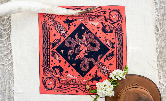 Bandits Rattle & Hiss bandana by Nuri Amanatullah featuring a coiled rattlesnake around a longhorn skull, surrounded by desert birds, wildflowers, stars, and Southwestern-inspired illustrations.