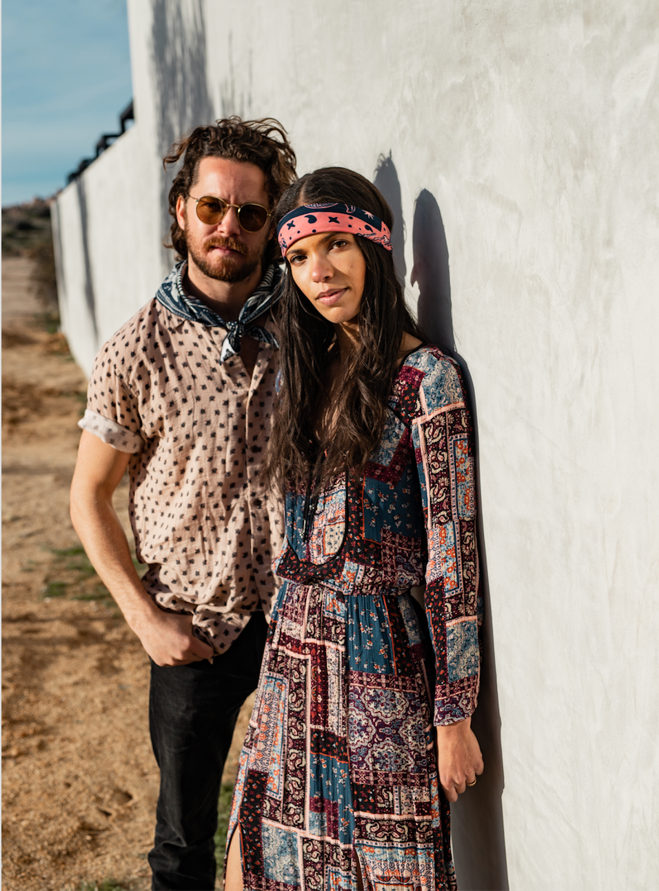 odel wearing the Bandits Rattle & Hiss bandana by Nuri Amanatullah as a headband while standing beside another model wearing a Bandits bandana as a neck scarf.