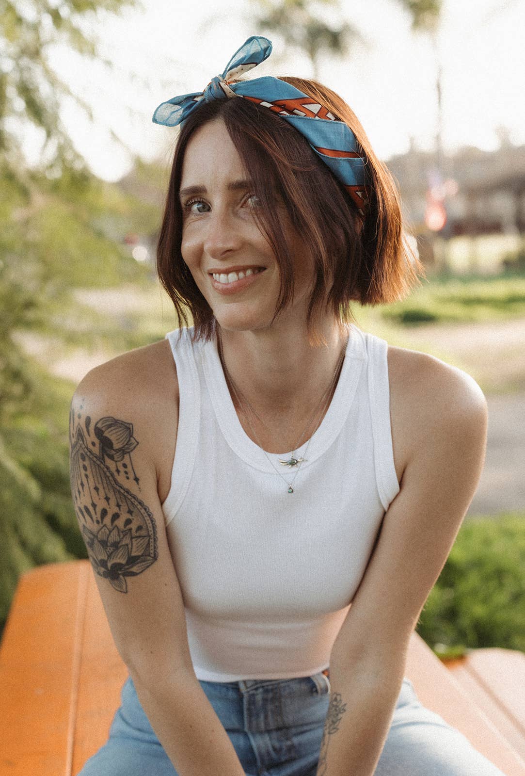 Model wearing the Bandits Van Berkemeyer Wild West bandana as a headband with a white tank top and denim jeans.