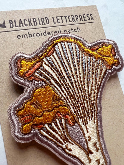 chanterelle mushroom patch, embroidered mushroom patch, golden mushroom iron-on, fungi sew-on patch, woodland embroidery patch, textured chanterelle applique, backpack mushroom patch, jean jacket patch, forager gift, artisan embroidered patch, blackbird letterpress patch, cottagecore mushroom accessory, nature lover patch, rogue & rye mushroom patch, embroidered chanterelle design