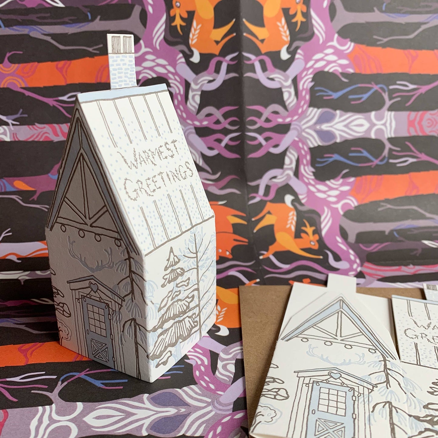 warmest greetings card, holiday cabin card, 3d house holiday card, winter cabin letterpress card, ice blue letterpress, forest brown letterpress, foldable holiday house card, buildable cabin card, die-cut Christmas card, miniature cabin card, artisan holiday stationery, Blackbird Letterpress holiday collection, Rogue & Rye holiday cards, winter greeting card, displayable paper craft card, Élise Lassonde illustration, A2 letterpress Christmas card