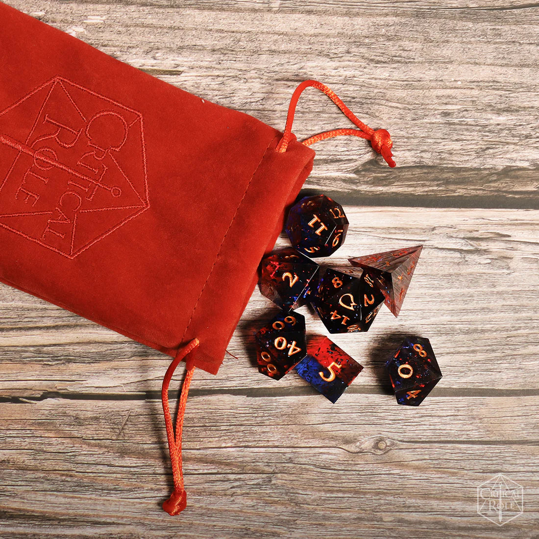 Critical Role Caleb Widogast Champion Dice Set by Darrington Press featuring maroon and blue sharp-edged resin dice with gold numbering.