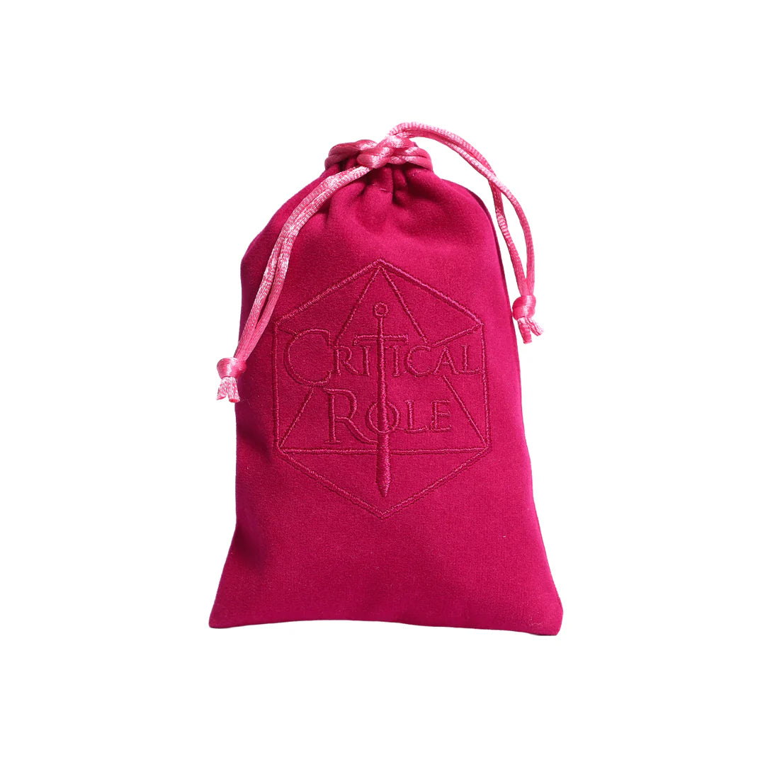 Dark pink velveteen drawstring bag included with the Critical Role Champion Dice Set inspired by Caduceus Clay. The bag features an embroidered Critical Role logo on the front and provides a soft, protective storage option for the nature-inspired sharp-edged resin dice.