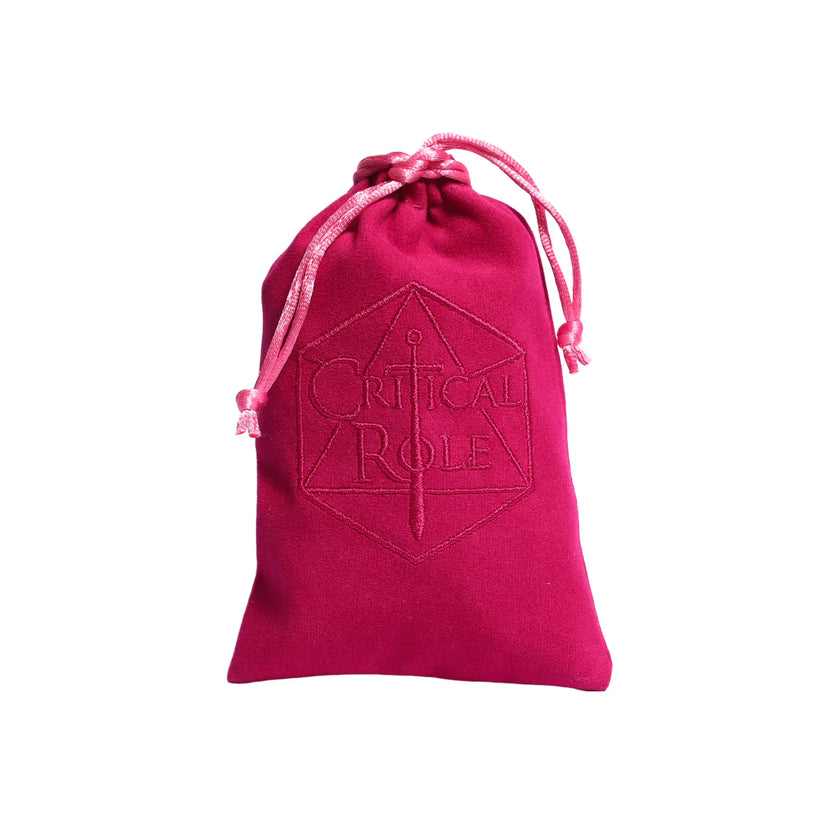 Dark pink velveteen drawstring bag included with the Critical Role Champion Dice Set inspired by Caduceus Clay. The bag features an embroidered Critical Role logo on the front and provides a soft, protective storage option for the nature-inspired sharp-edged resin dice.