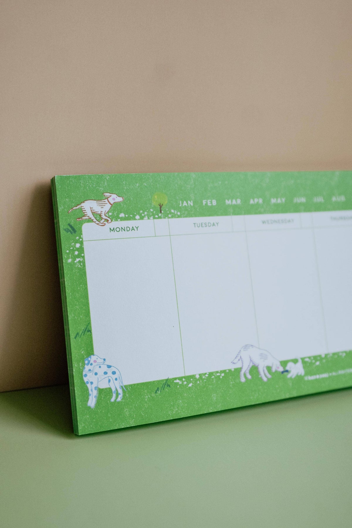 Long green Dog Days weekly desk planner displayed upright