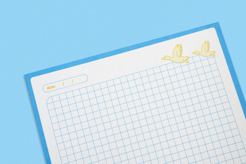 Light blue grid paper and flying duck illustrations on the notepad