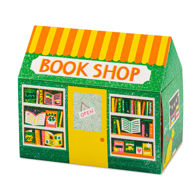 Bookshop matchbox, house-shaped safety matches, The Printed Peanut illustration, bookstore matchbox design, book lover gifts, bibliophile accessories, Archivist House Match collection, whimsical illustrated matchbox, UK-made safety matches, reading nook décor, collectible matchbox art, Rogue & Rye curated gifts, colorful bookshop artwork, artisan matchboxes.