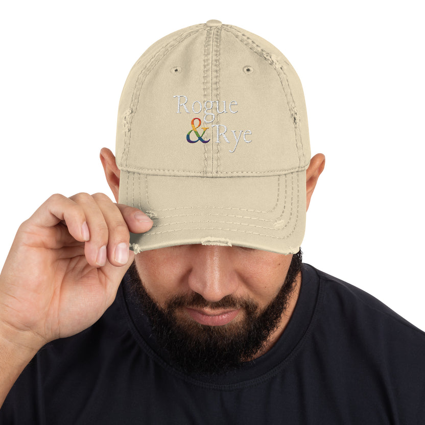 and well-worn pride cap, distressed pride hat, inclusive embroidered hat, rogue and rye lgbtq gear, queer and proud cap, lived-in pride cap, soft cotton twill hat, outright international donation, evolving identity hat, rogue and rye pride collection, gender inclusive pride wear, adjustable distressed cap, embroidered and message, everyday queer pride gear, unstructured pride cap, pride fashion hat, lgbtq supportive cap