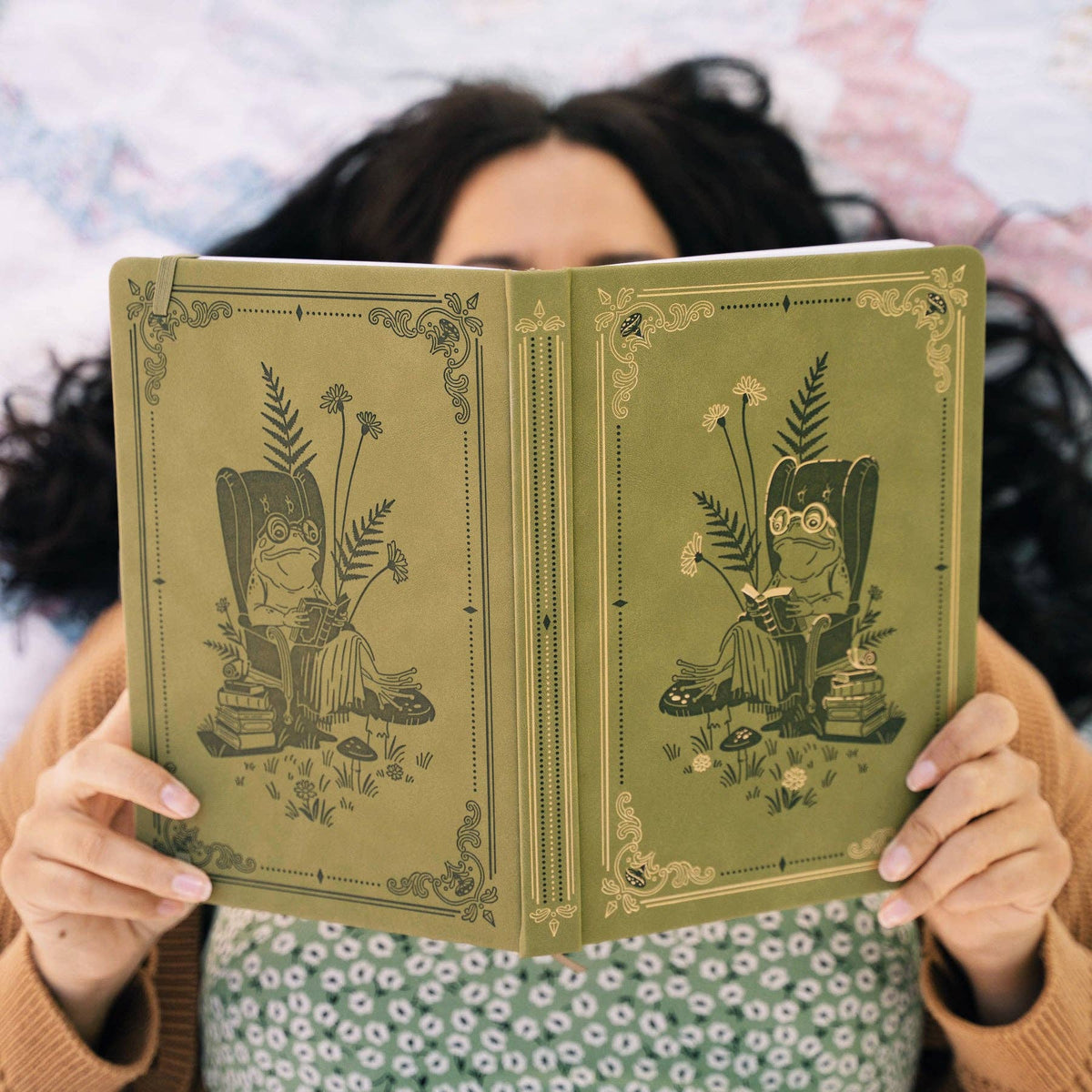 Person holding open Literary Frog notebook with illustrated front and back covers