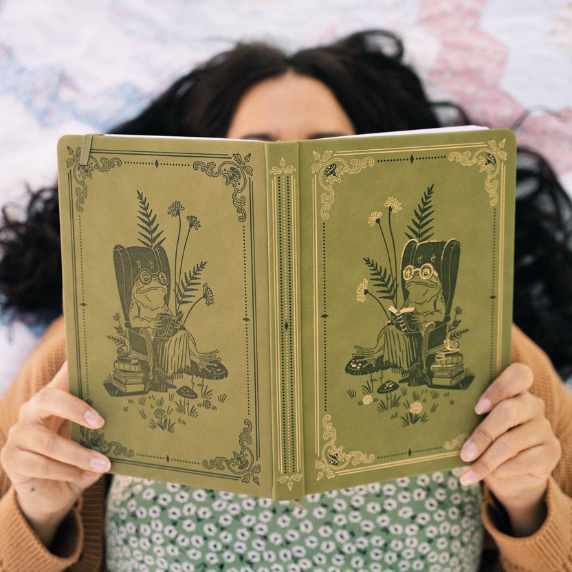 Person holding open Literary Frog notebook with illustrated front and back covers