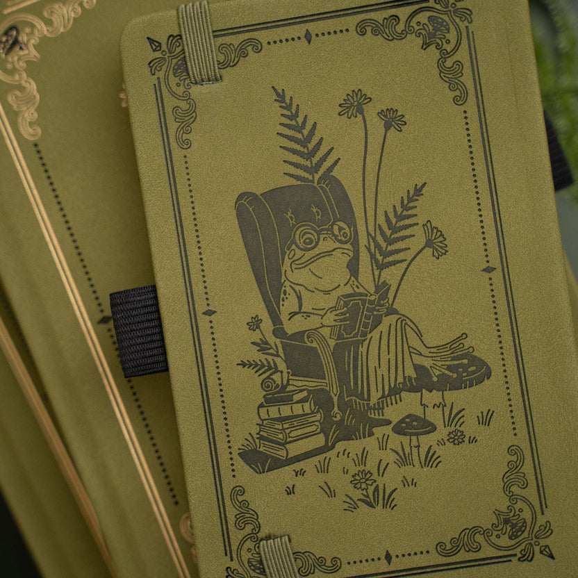 Literary Frog notebook with reading frog, books, mushrooms, and woodland plants