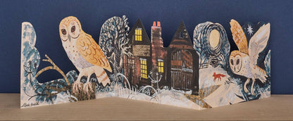 Mark Hearld Silent Flight accordion greeting card opened to display illustrated owls, woodland cottages, snowy trees, and a winter landscape.