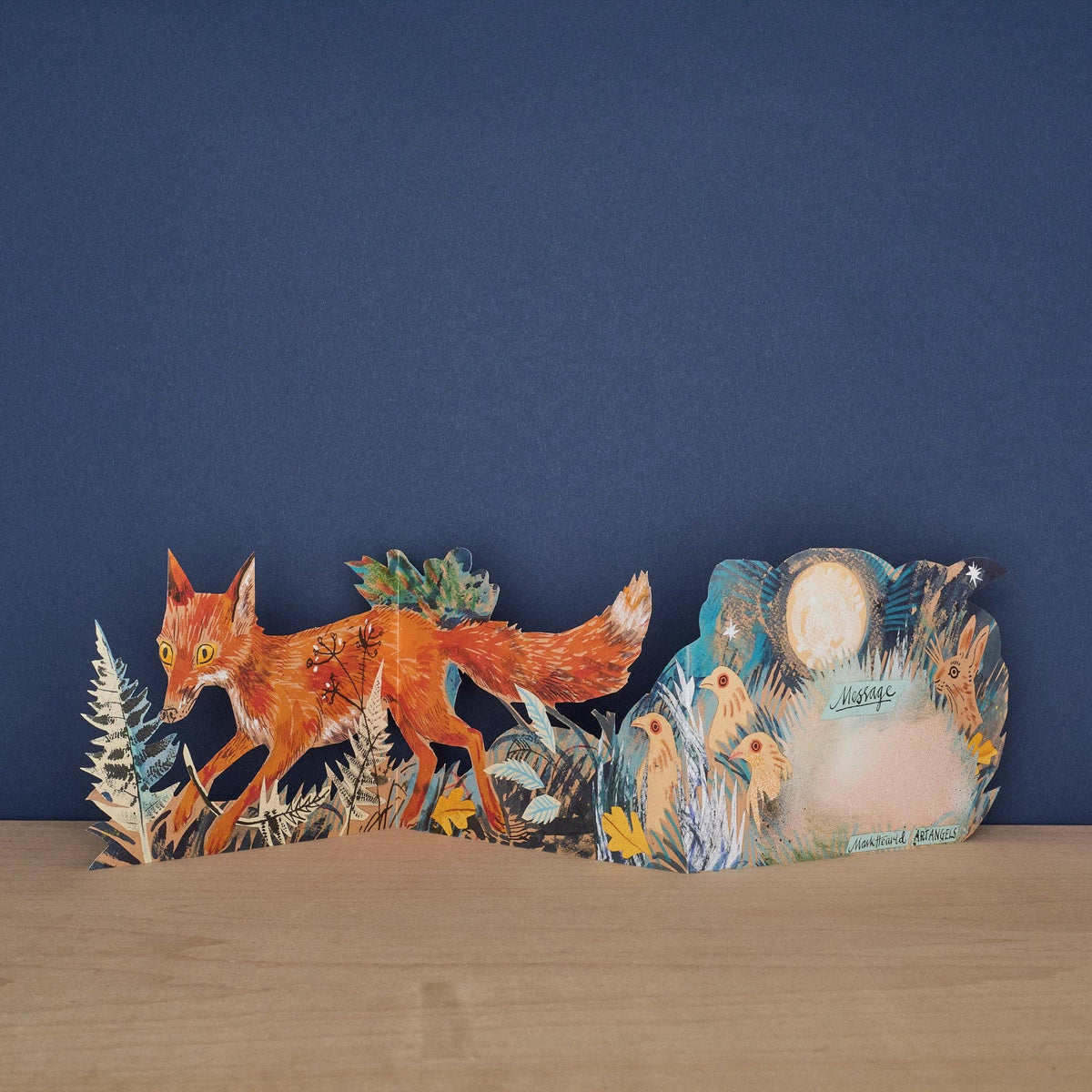 Mark Hearld Three Fold Fox accordion greeting card showing the hidden moon-shaped message panel surrounded by a fox, woodland birds, and a moonlit woodland scene.