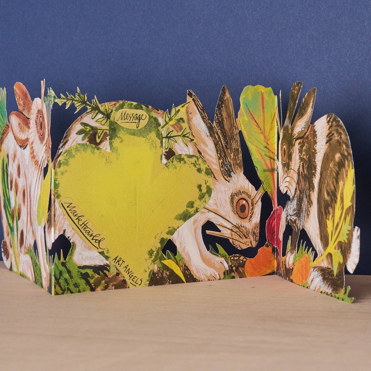 Mark Hearld Three Fold Rabbits accordion greeting card showing the hidden clover-shaped message panel surrounded by illustrated rabbits and woodland foliage.