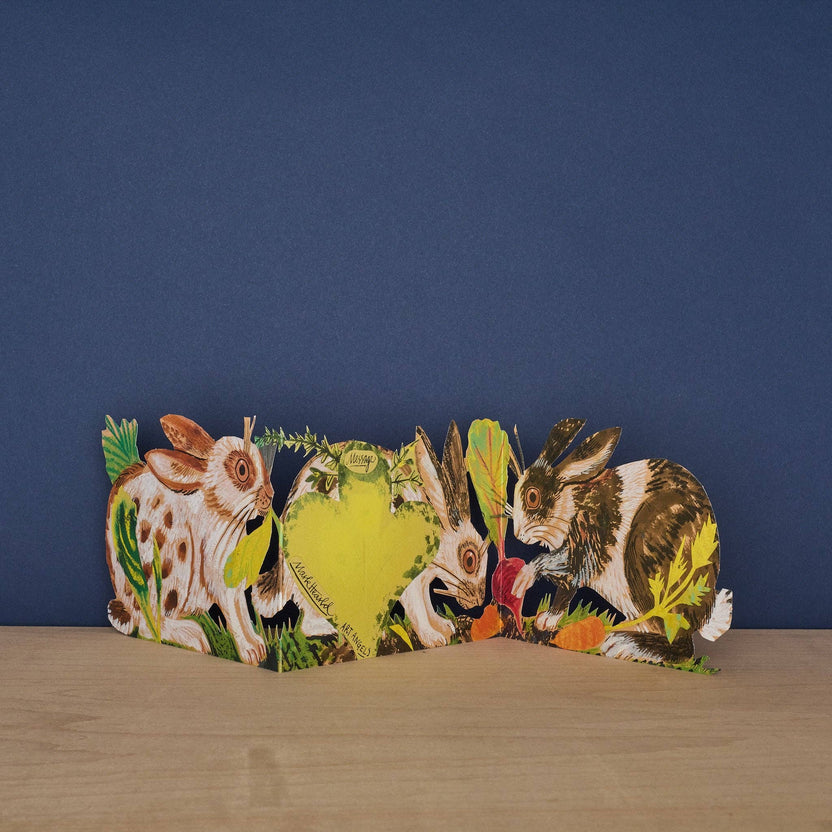 Mark Hearld Three Fold Rabbits accordion greeting card showing the hidden clover-shaped message panel surrounded by illustrated rabbits and woodland foliage.